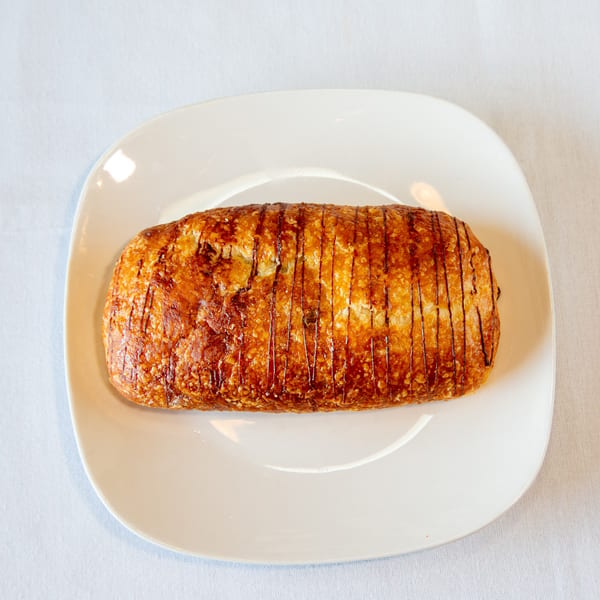 Golden-brown pastry with dark lines on a white rectangular plate.