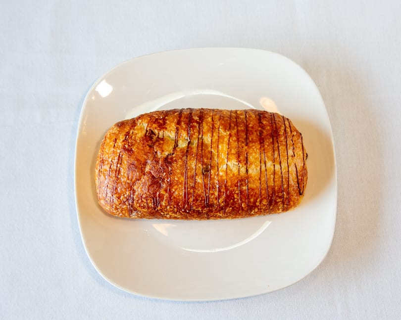 Golden-brown pastry with dark lines on a white rectangular plate.